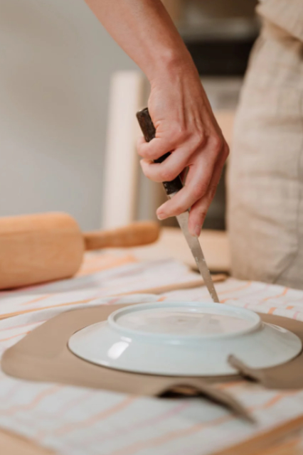 ceramiczka wycina nozem gline w ksztalcie talerza